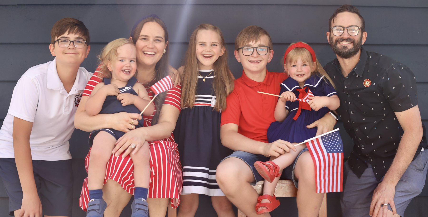 Family portrait of the Temporary Totes owner with his wife and five children, dressed in red, white, and blue.